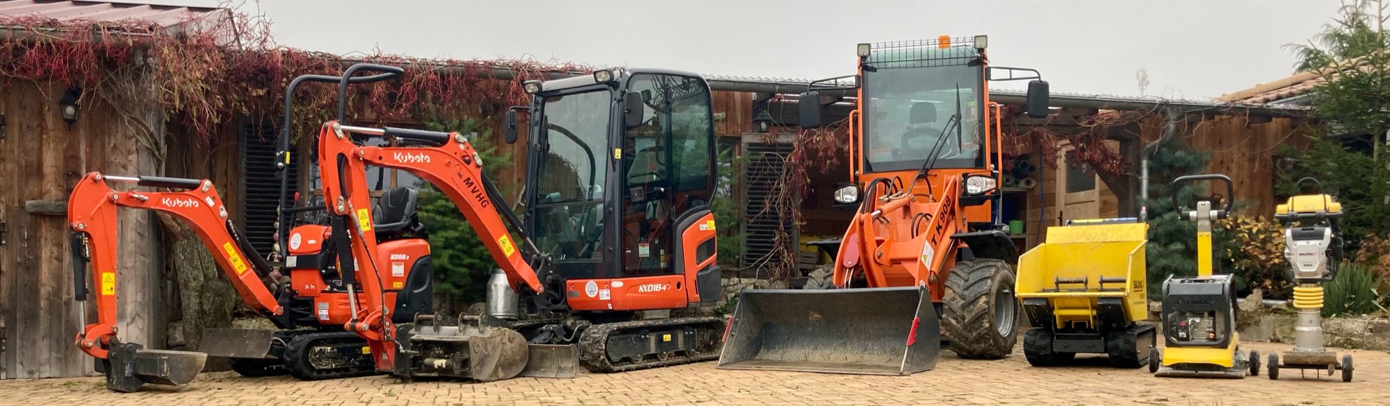 Maschinen aus dem Mietpark von MVHG nebeneinander auf dem Hof: zwei Minibagger, ein Radlader, ein Dumper, eine Rüttelplatte und ein Stampfer.