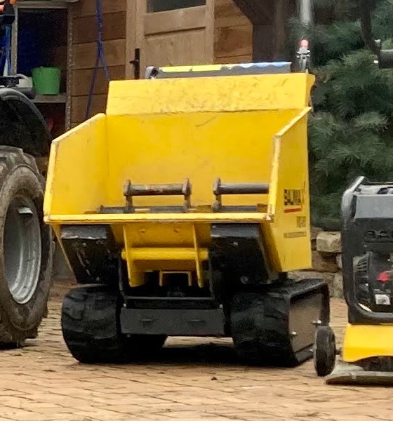 Gelber Dumper mit Kippmulde auf Raupenfahrwerk.